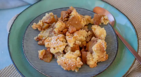 Ein Teller mit köstlichem Apfel-Crumble, bestäubt mit Puderzucker. Die warmen Apfelstücke und die knusprige Streuselhaube laden zum Genießen ein.