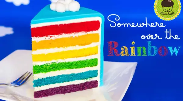 Ein Stück regenbogen kuchen mit bunten Schichten und Wolken-Topping.