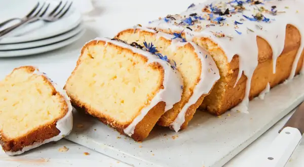 Saftiger Kuchen mit Mascarpone, verziert mit blauen Blüten und Zuckerguss.