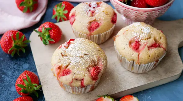 Saftige Erdbeermuffins, perfekt für jeden Kindergeburtstag, mit Puderzucker bestäubt und frischen Erdbeeren garniert.