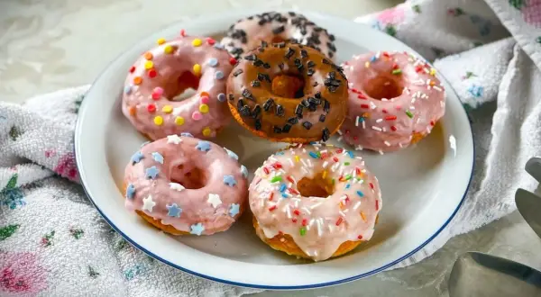 Sechs bunte Donuts mit Streuseln und Sternen auf einem Teller, ein köstliches Donuts Rezept für jeden Anlass.