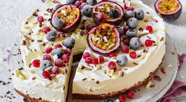 Ein erfrischender Sommerkuchen mit cremiger Füllung, garniert mit Passionsfrucht, Blaubeeren und roten Johannisbeeren.