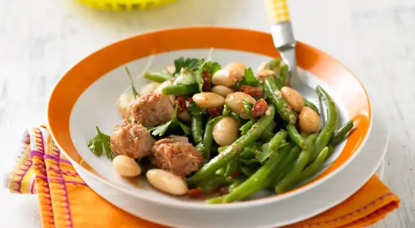 Bohnensalat rezept: Frischer Bohnensalat mit weißen Bohnen, grünen Bohnen, Thunfisch und Kräutern auf einem Teller mit orangem Rand.