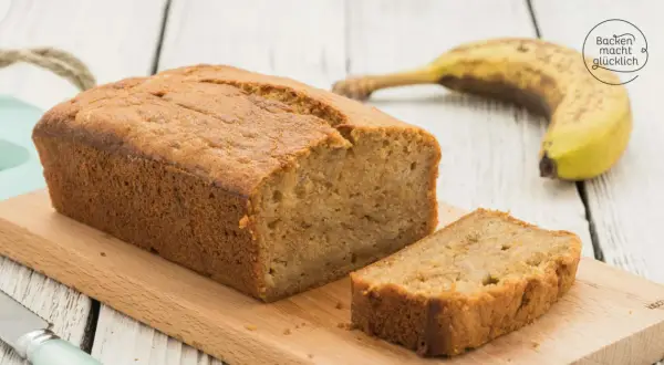 Saftiges Bananenbrot mit Dinkelmehl, frisch gebacken und auf einem Holzbrett angerichtet. Eine Scheibe ist bereits abgeschnitten.