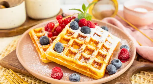 Goldene protein waffeln rezept mit frischen Beeren und Puderzucker bestäubt. Ein köstlicher Start in den Tag!