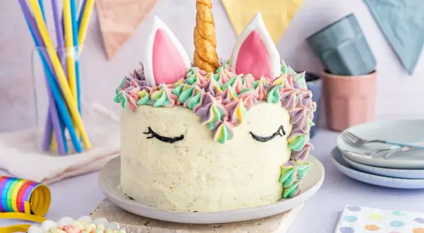 Ein magischer einhorn kuchen mit bunten Tupfen und einem goldenen Horn. Perfekt für eine märchenhafte Feier.