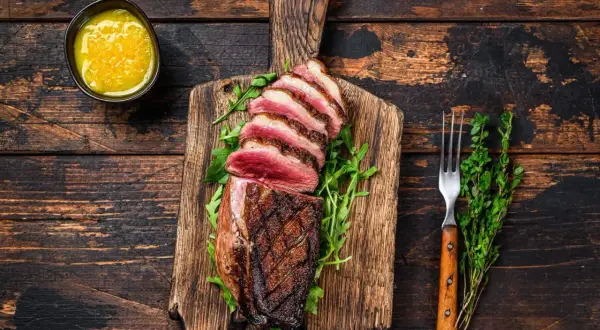 Perfekt gegrillte Ente auf Holzbrett, mit Rucola und Sauce. Die Kerntemperatur der Ente messen ist wichtig für den perfekten Garpunkt.