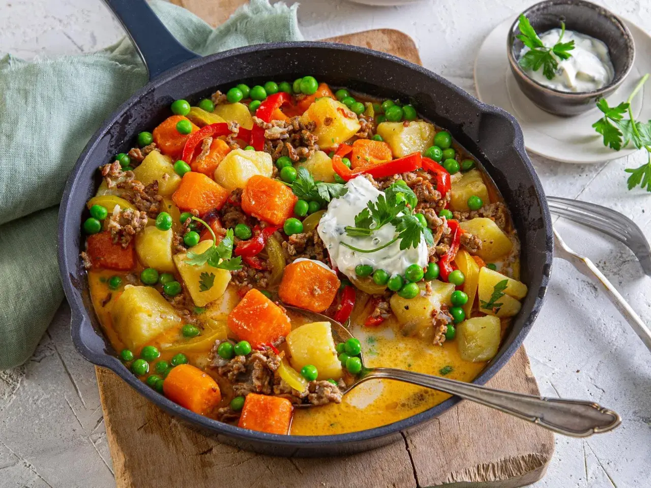Herzhafte Hackfleischpfanne mit Kartoffeln, Karotten und Erbsen. Eine tolle Idee für ein schnelles Abendessen, garniert mit frischer Petersilie und einem Klecks Sour Cream.