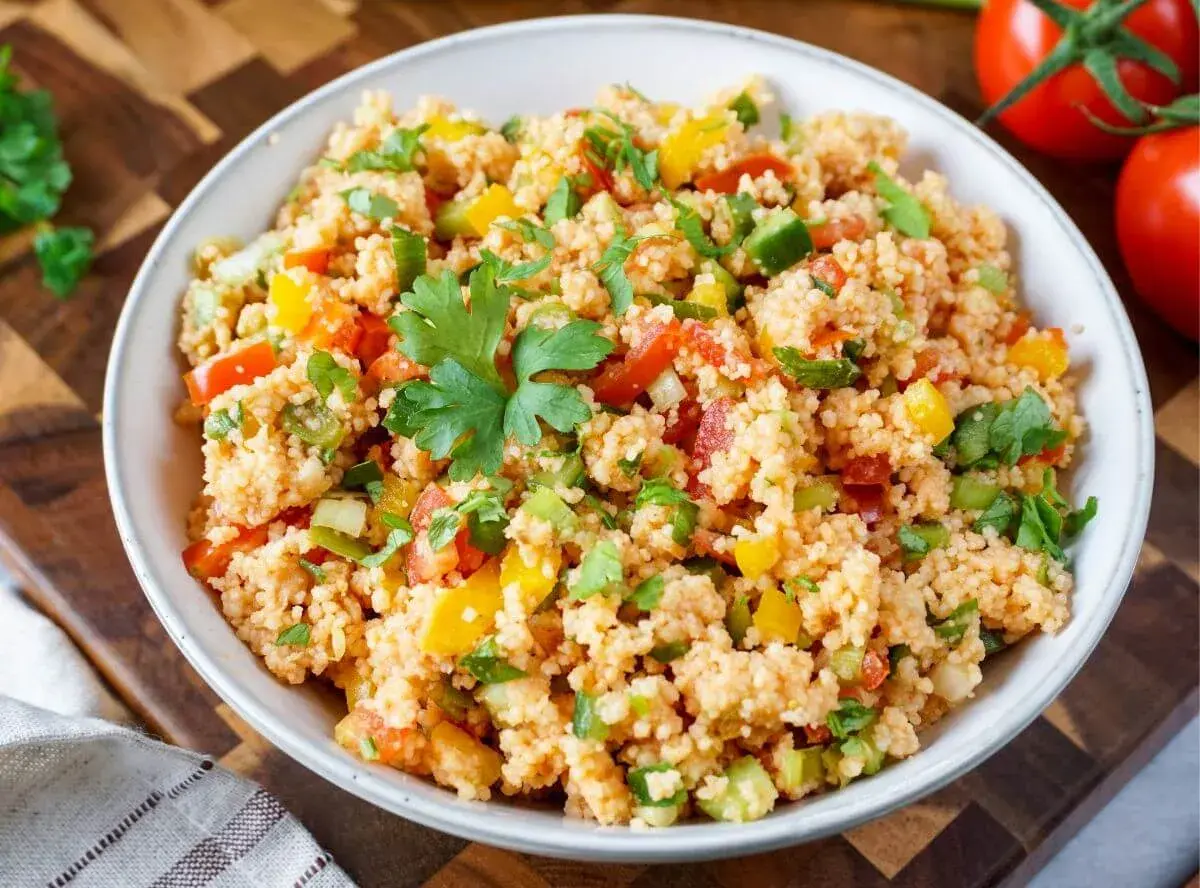 Bunter Couscous-Salat mit Tomaten, Paprika und frischer Petersilie, garniert mit einem Petersilienblatt.