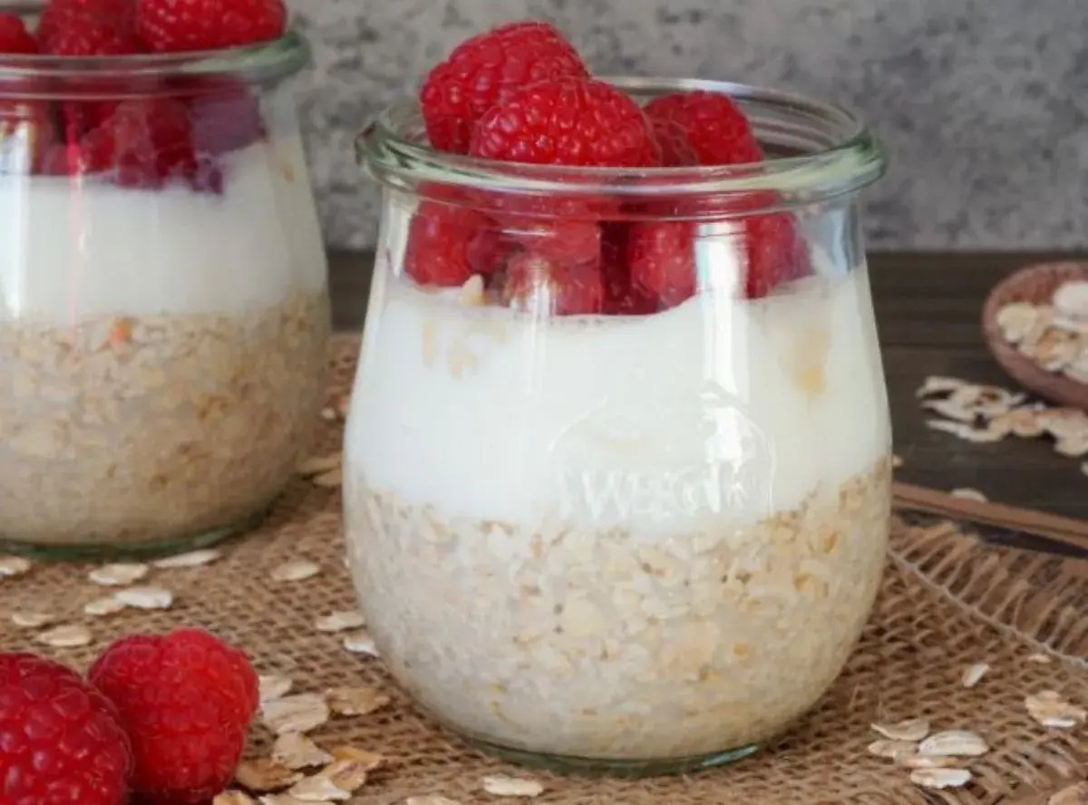 Zwei Gläser mit overnight oats mit joghurt und frischen Himbeeren. Ein gesunder Start in den Tag.