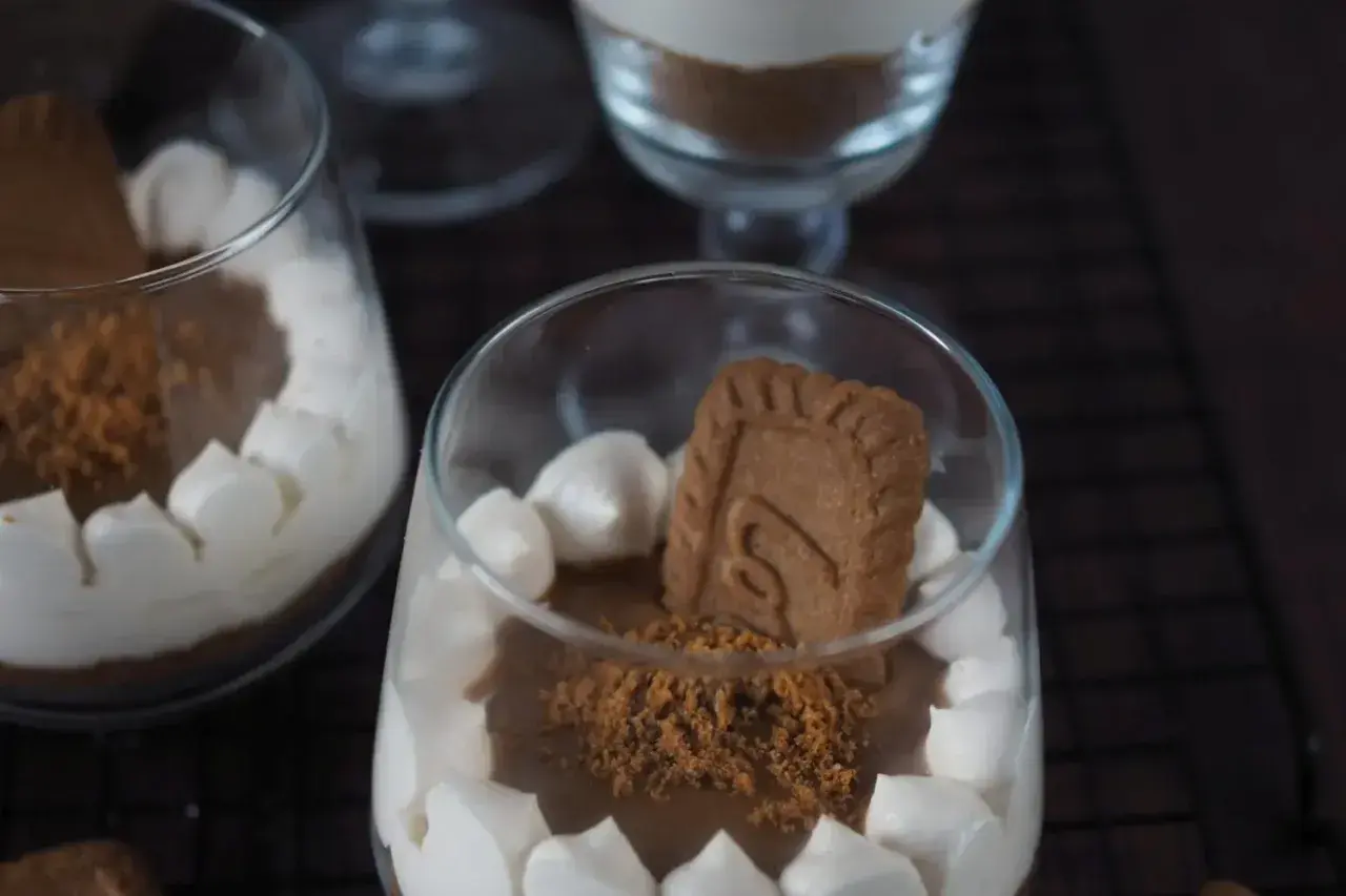 Cremiges Lotus Dessert im Glas, garniert mit Keksstückchen und einem ganzen Keks.