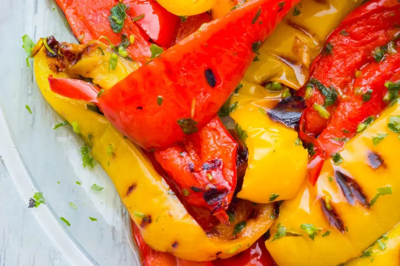 Leckeres Paprika grillen mit Kräutern. Rote und gelbe Paprikastreifen sind saftig und leicht angekohlt.