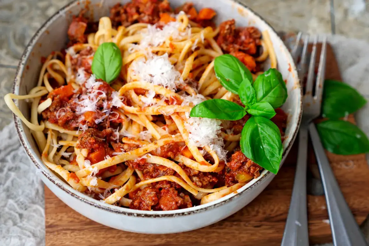 Eine Schüssel mit Linguine und einer herzhaften, **schnellen Bolognese** Soße, garniert mit frischem Basilikum und Parmesan.