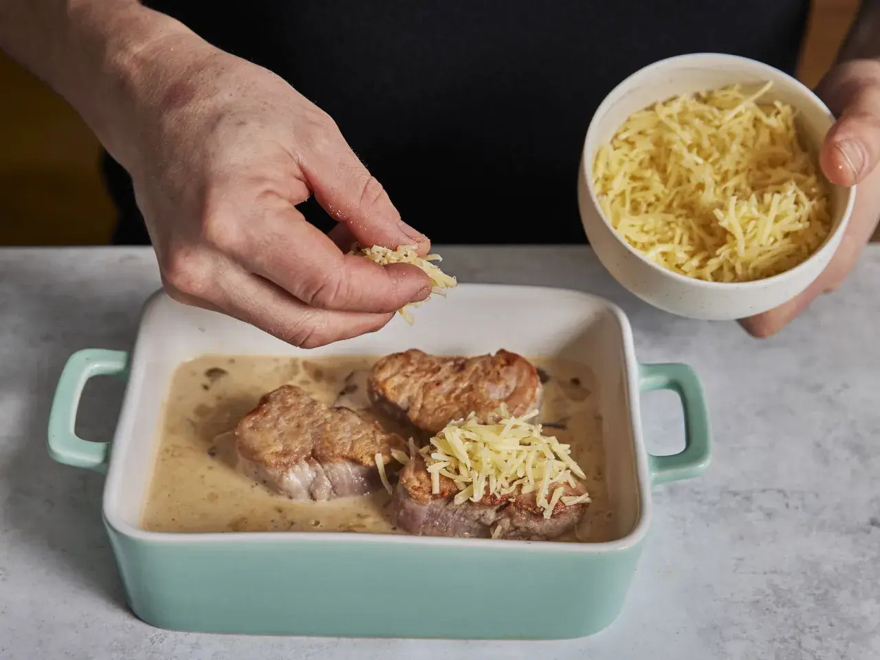 Zarte schweine medaillons in cremiger Sauce werden mit geriebenem Käse bestreut.