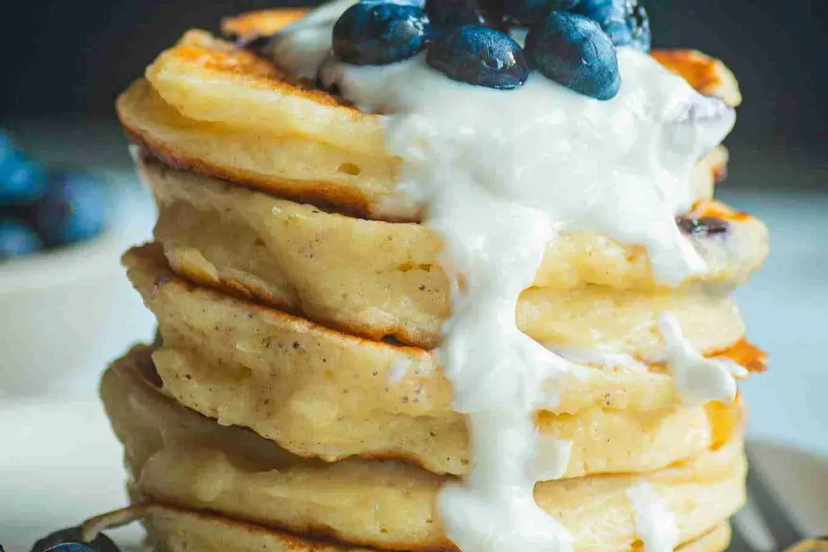 Ein Stapel fluffiger Protein Pancakes mit Blaubeeren und Joghurt. Perfekt für ein gesundes Frühstück, inspiriert von einem protein pancakes rezept.