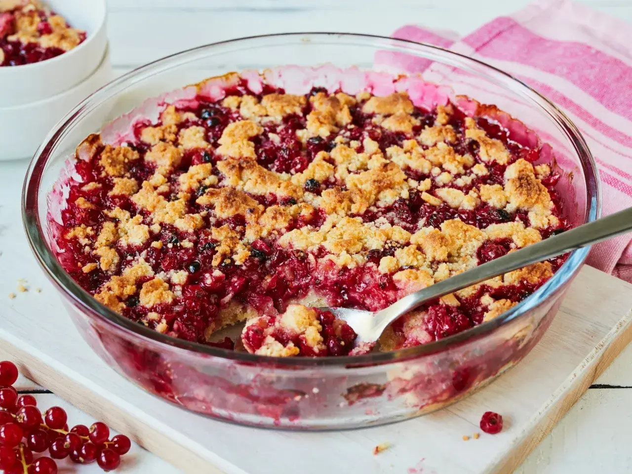 Ein leckerer Johannisbeer Crumble in einer Glasform, mit knuspriger Streuselhaube und saftiger roter Füllung.