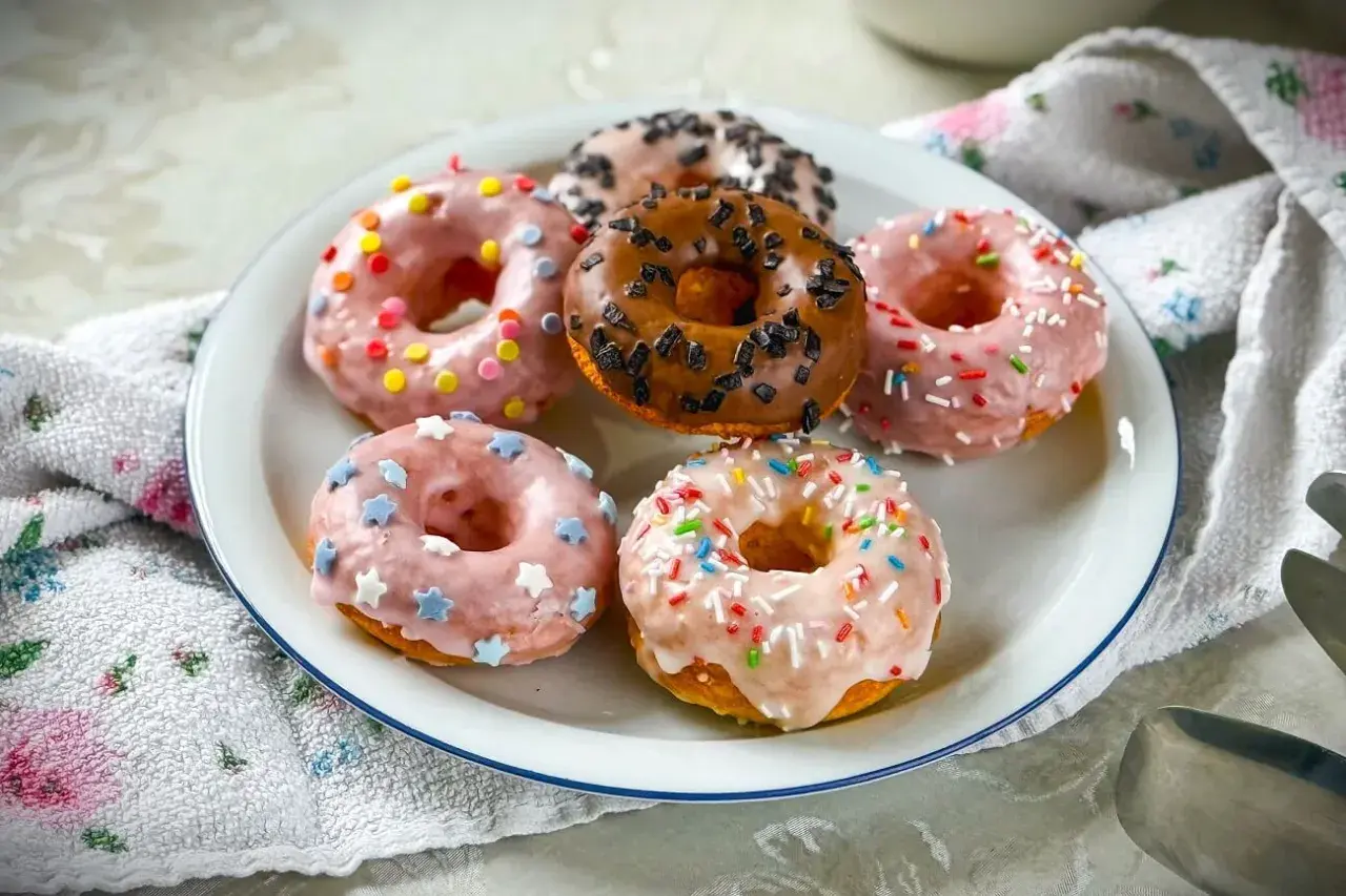 Sechs bunte Donuts mit Streuseln und Sternen auf einem Teller, ein köstliches Donuts Rezept für jeden Anlass.
