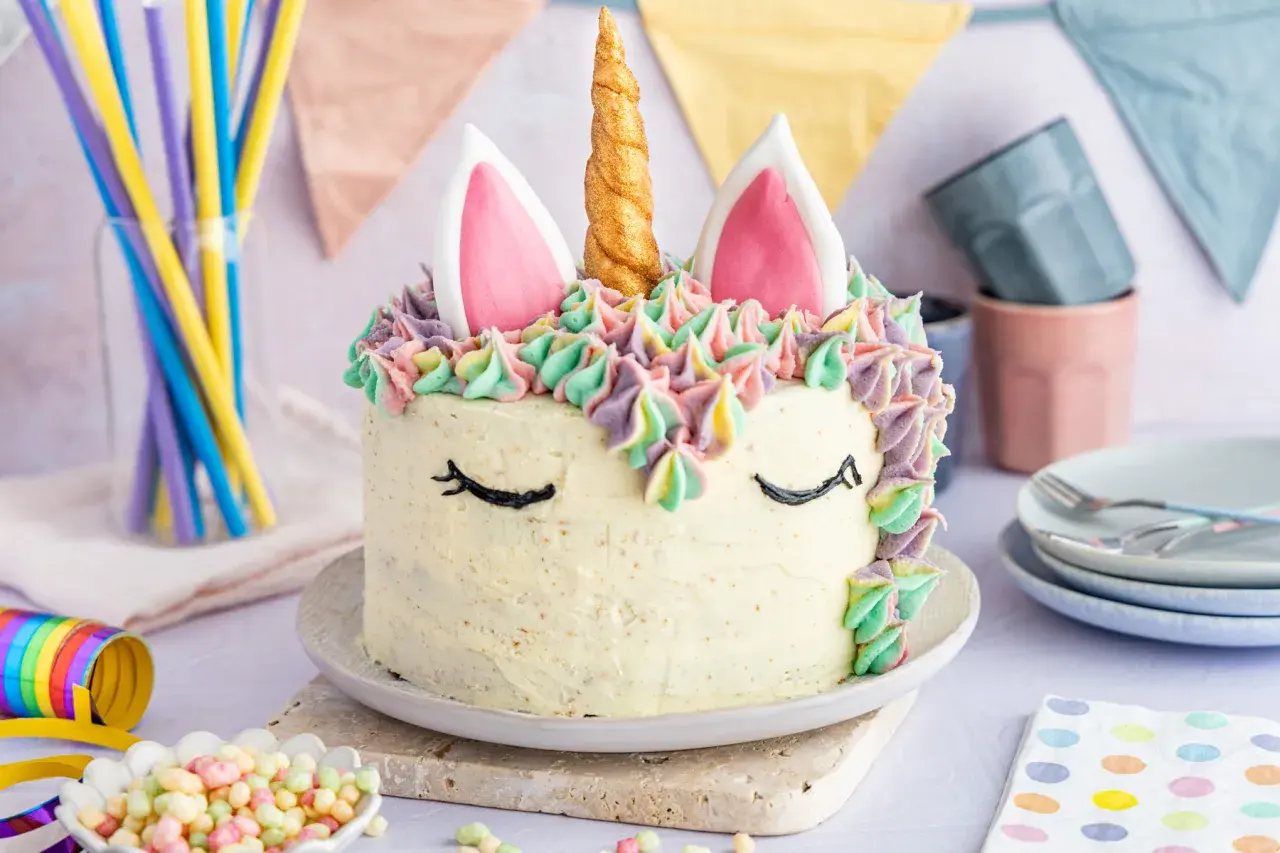 Ein magischer einhorn kuchen mit bunten Tupfen und einem goldenen Horn. Perfekt für eine märchenhafte Feier.