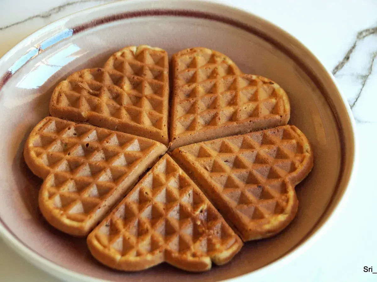 Herzförmige Waffeln ohne Zucker, goldbraun gebacken, liegen auf einem Teller.