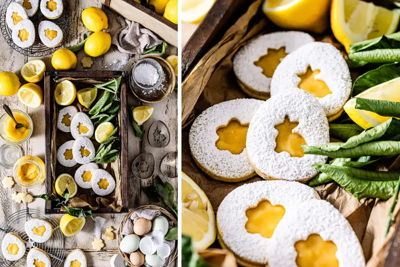 Osterkekse mit Zitrone und Puderzucker, gefüllt mit leckerer Zitronencreme. Frische Zitronen und grüne Blätter umgeben die süßen Leckereien.