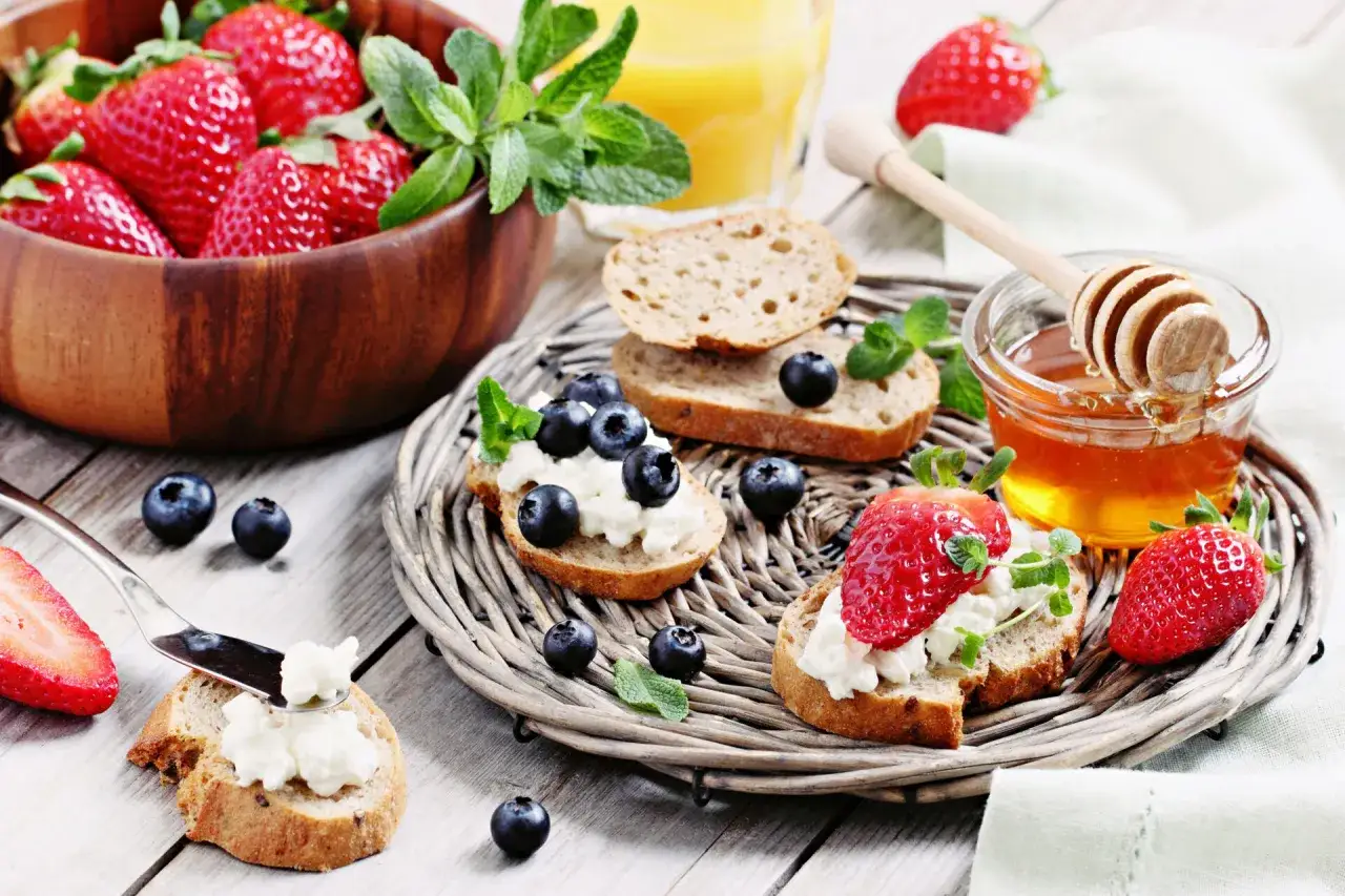 Leckere Brunch-Ideen: Crostini mit Frischk&auml;se, Beeren und Honig. Frische Erdbeeren und Blaubeeren auf Brot mit Minze.