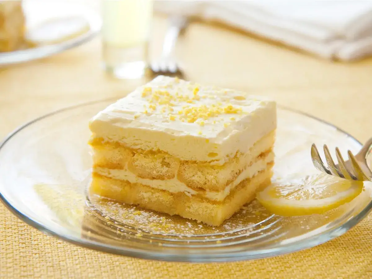 Ein St&uuml;ck Limoncello Tiramisu auf einem Teller, garniert mit Zitronenschale.