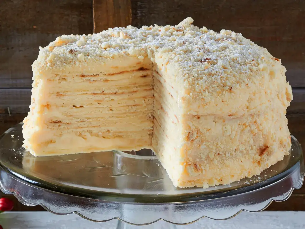 Ein aufgeschnittener Napoleon Kuchen mit vielen d&uuml;nnen Schichten und cremiger F&uuml;llung, bestreut mit Kr&uuml;meln.