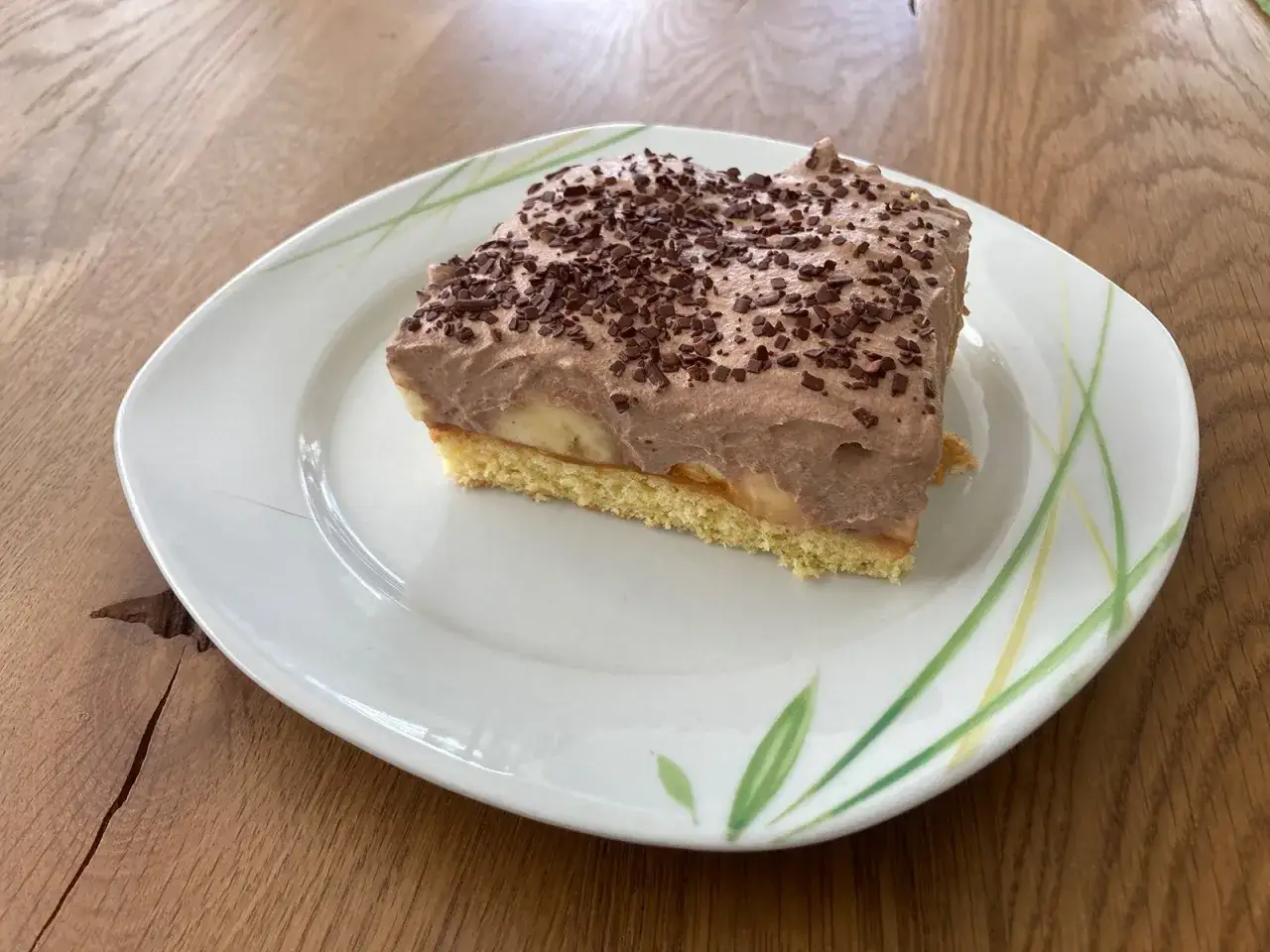 Ein St&uuml;ck saftiger Maulwurfkuchen vom Blech mit Bananen und Schokocreme, bestreut mit Schokostreuseln.