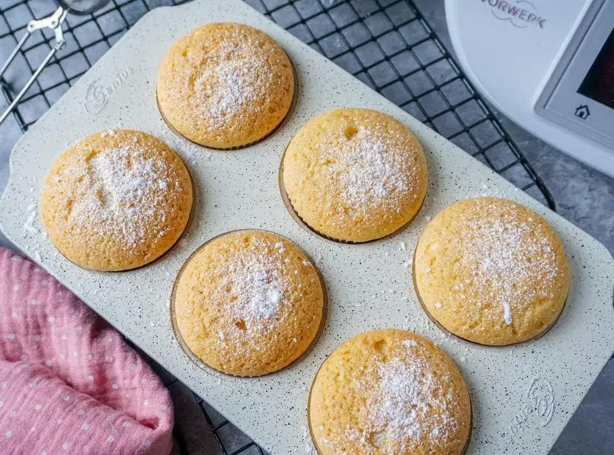 Sechs goldbraune Muffins, mit Puderzucker best&auml;ubt, auf einer hellen Backform. Perfekt f&uuml;r den Thermomix!