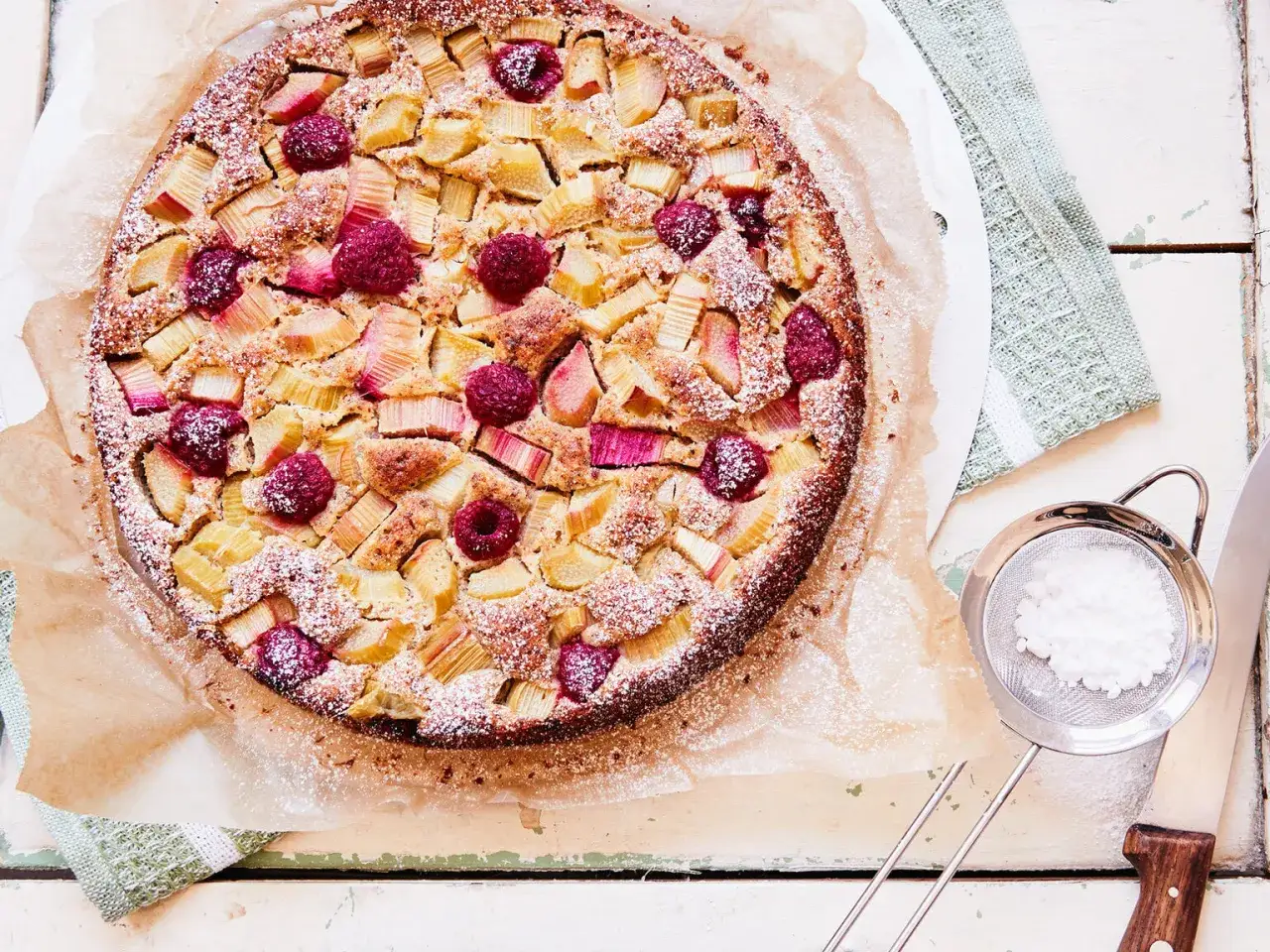 Ein k&ouml;stlicher low carb rhabarberkuchen mit Himbeeren, best&auml;ubt mit Puderzucker. Perfekt f&uuml;r den Sommer!