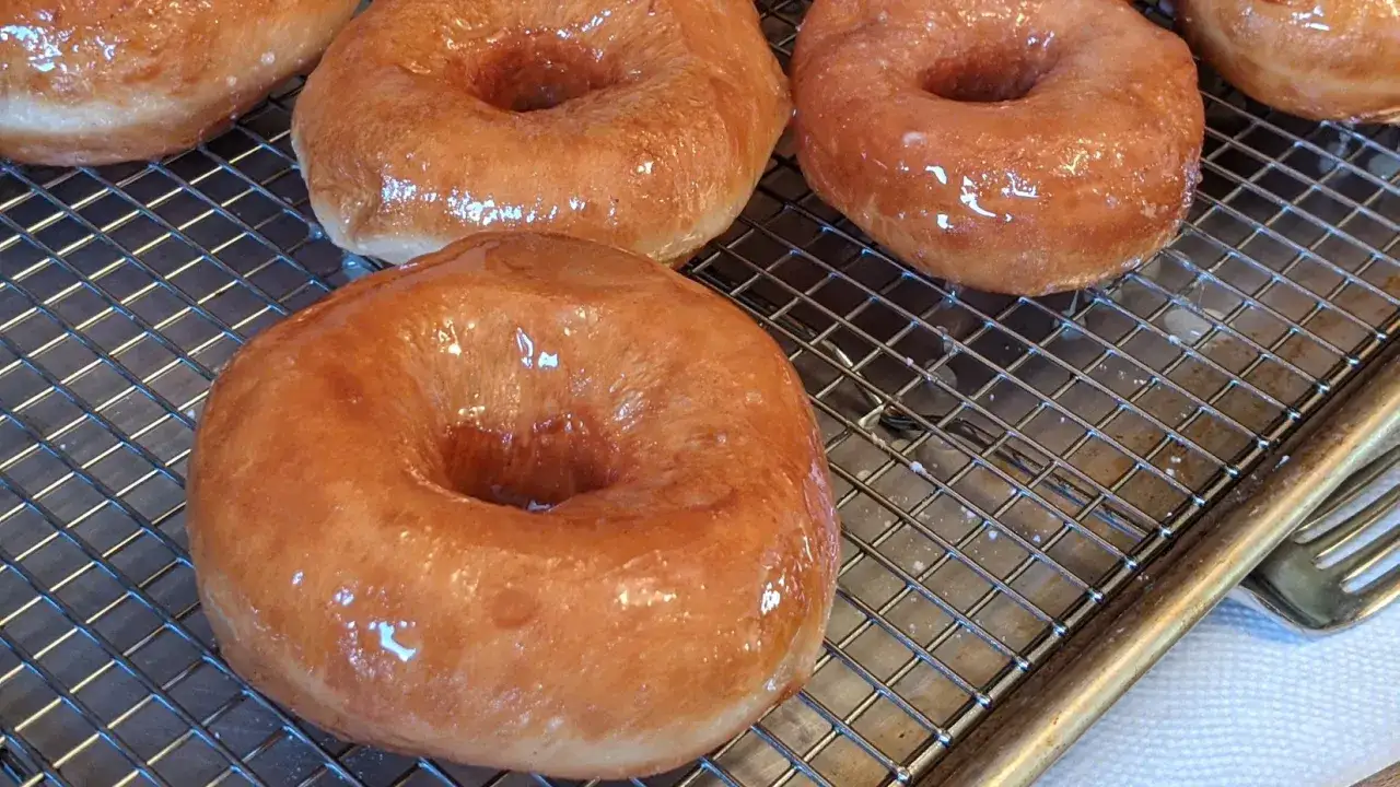 Frisch gebackene, glasierte Donuts auf einem Gitter. Ein perfektes Donuts Rezept für süße Momente.