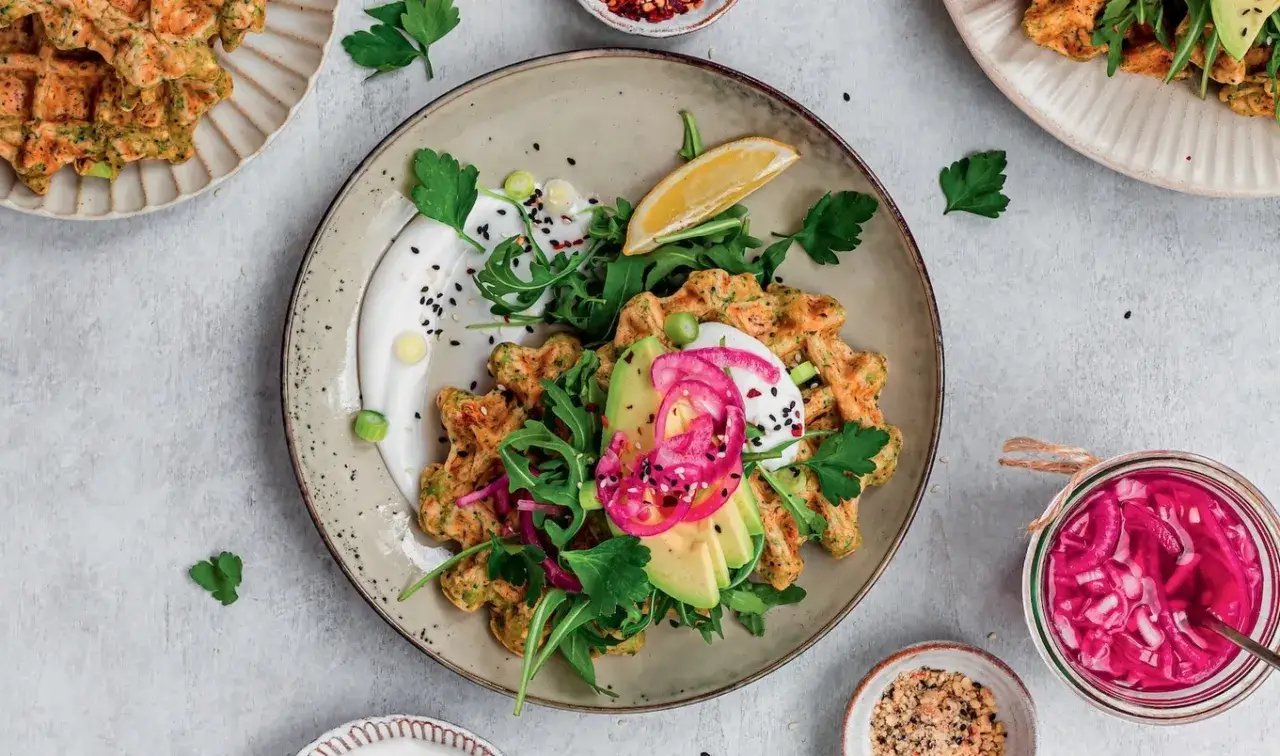 Herzhafte vegane Waffeln mit Avocado, Rucola und eingelegten Zwiebeln. Ein köstliches, gesundes Gericht.