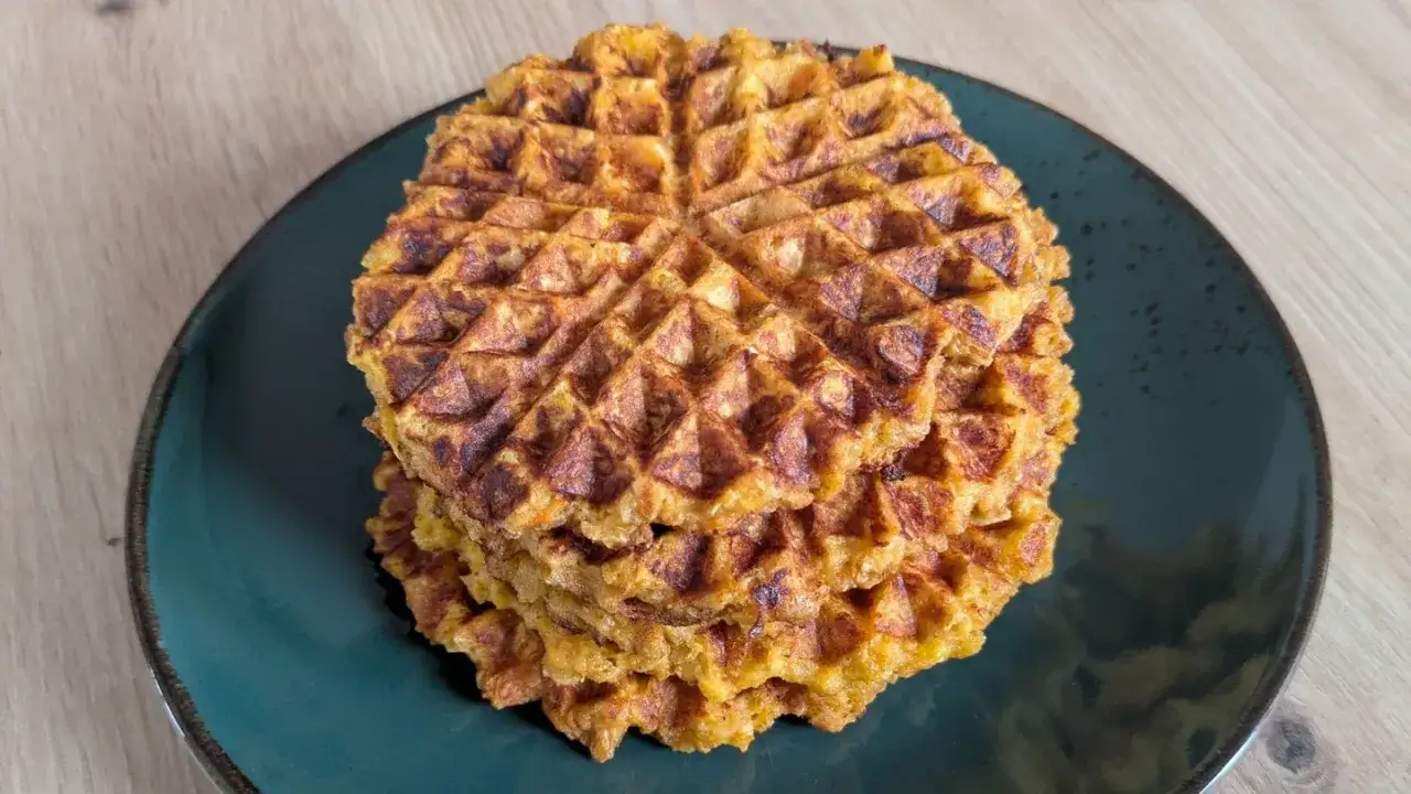 Ein Stapel goldbrauner Haferflocken Waffeln auf einem dunklen Teller.