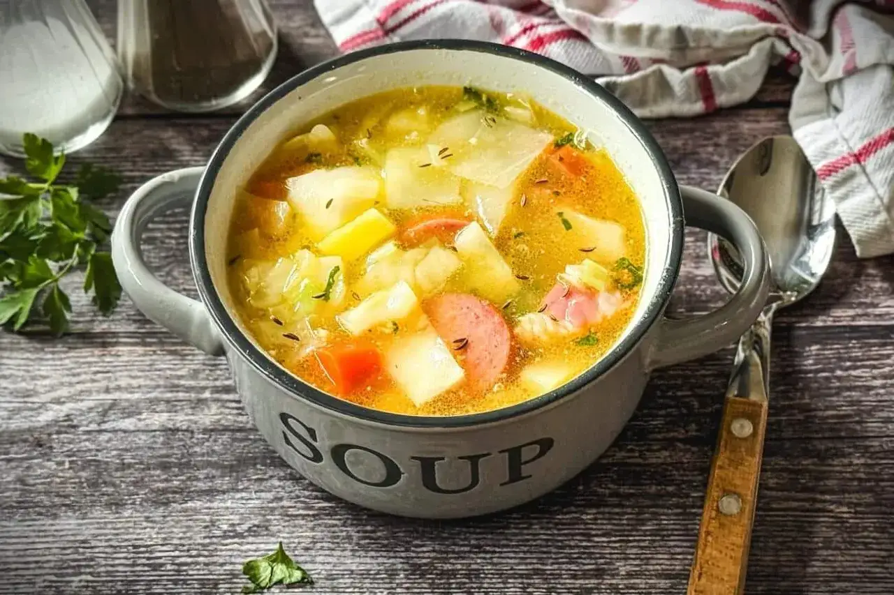 Herzhaftes Kohlsuppe Rezept mit Kartoffeln und Wurst in einer grauen Schüssel, bereit zum Genießen.