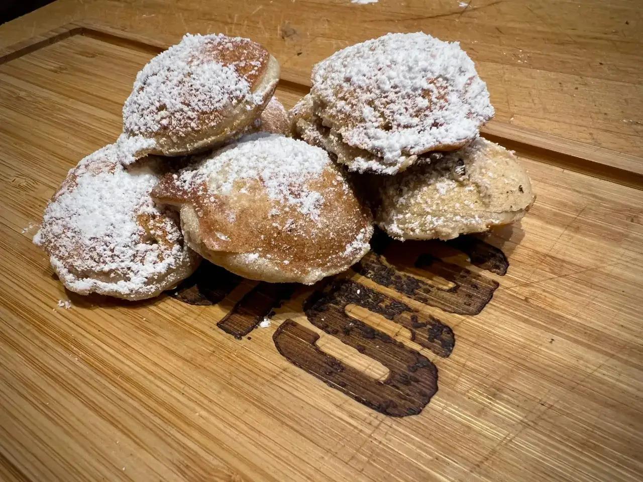 Ein Haufen frisch gebackener Poffertjes, bestäubt mit Puderzucker, wartet auf das Poffertjes Rezept.