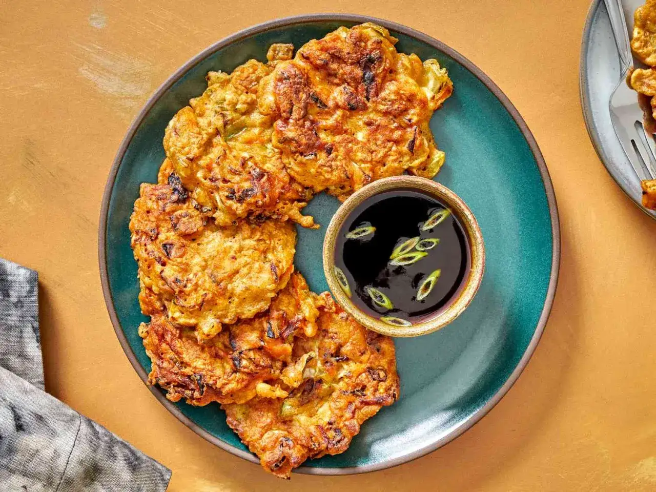 Deftige Pancakes mit Zwiebeln und einer dunklen Dip-Sauce, garniert mit Frühlingszwiebeln.