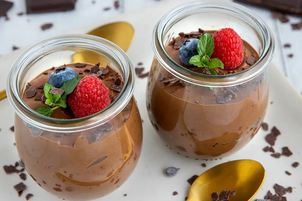 Zwei Gl&auml;ser mit cremigem Mousse au Chocolat, garniert mit Himbeeren, Blaubeeren und Minze. Ein k&ouml;stliches Rezept f&uuml;r Mousse au Chocolat.