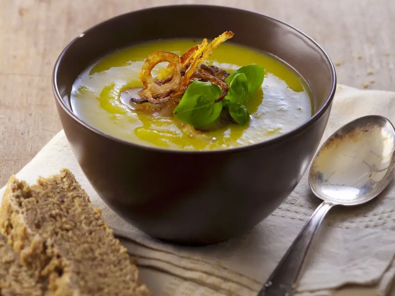 Cremige Lauchsuppe mit knusprigen Ringen und Basilikum. Ein k&ouml;stliches Rezept f&uuml;r Lauchcremesuppe, serviert mit Brot.
