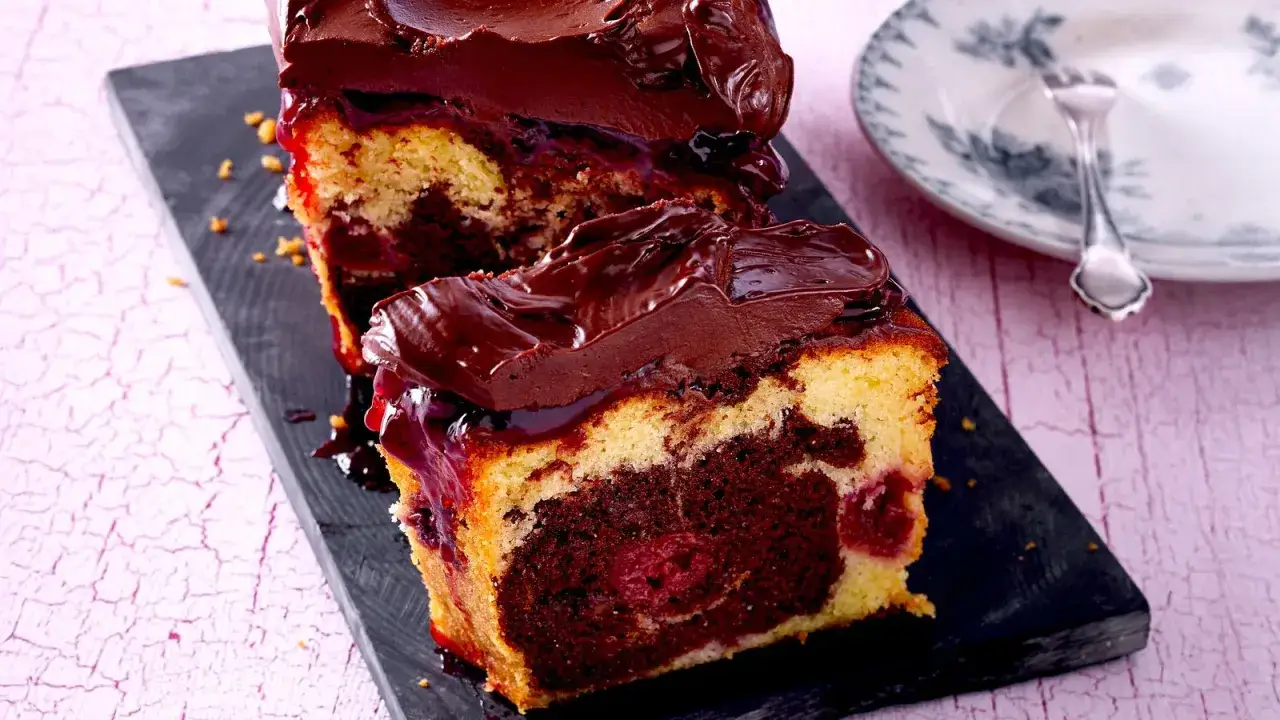 Zwei St&uuml;cke saftiger Marmorkuchen mit Kirschen, &uuml;berzogen mit dunkler Schokoladenglasur.
