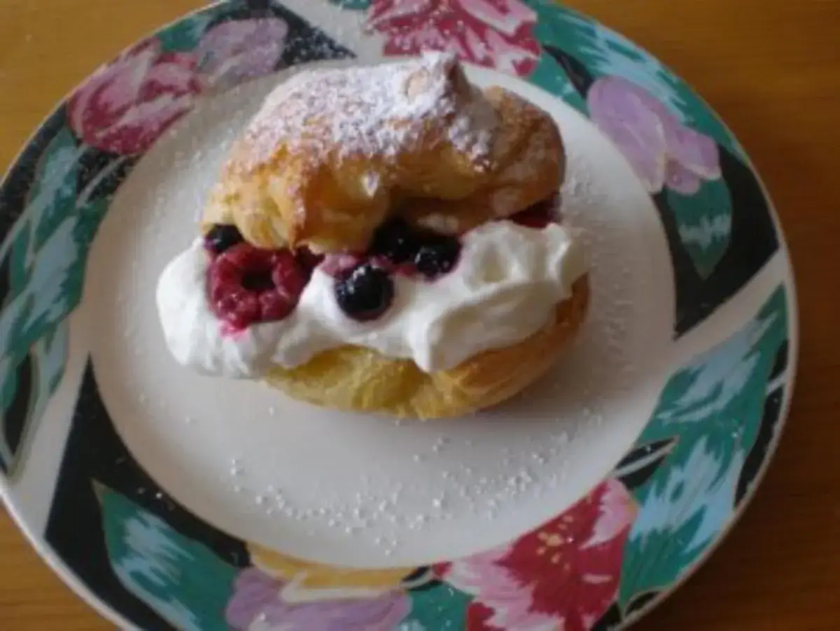 Ein k&ouml;stlicher Windbeutel gef&uuml;llt mit Sahne und frischen Beeren, best&auml;ubt mit Puderzucker. Ein s&uuml;&szlig;er Genuss!