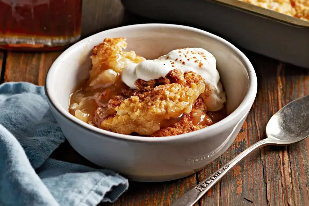 Ein k&ouml;stlicher warmer Nachtisch mit Apfel-Crumble und Sahne, bestreut mit Zimt. Perfekt f&uuml;r kalte Abende.