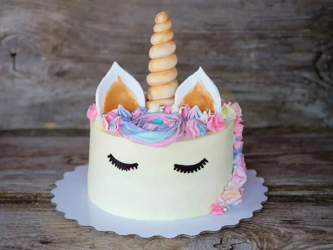 Ein magischer einhorn kuchen mit pastellfarbener Glasur, einem gedrehten Horn und s&uuml;&szlig;en Wimpern.
