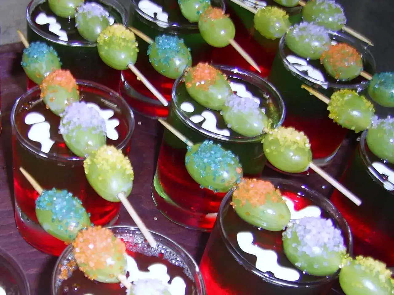 Gr&uuml;ne Trauben auf Spie&szlig;en, verziert mit bunten Zuckerstreuseln, schwimmen in roten und gr&uuml;nen Wackelpudding-Gl&auml;sern. Lustige Wackelpudding-Ideen f&uuml;r jede Party!