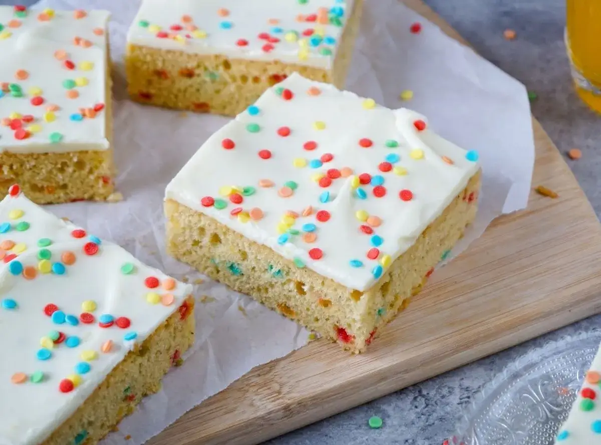 Bunte Streusel zieren den weißen Zuckerguss auf diesen leckeren Stücken eines Papageienkuchen-Rezepts.