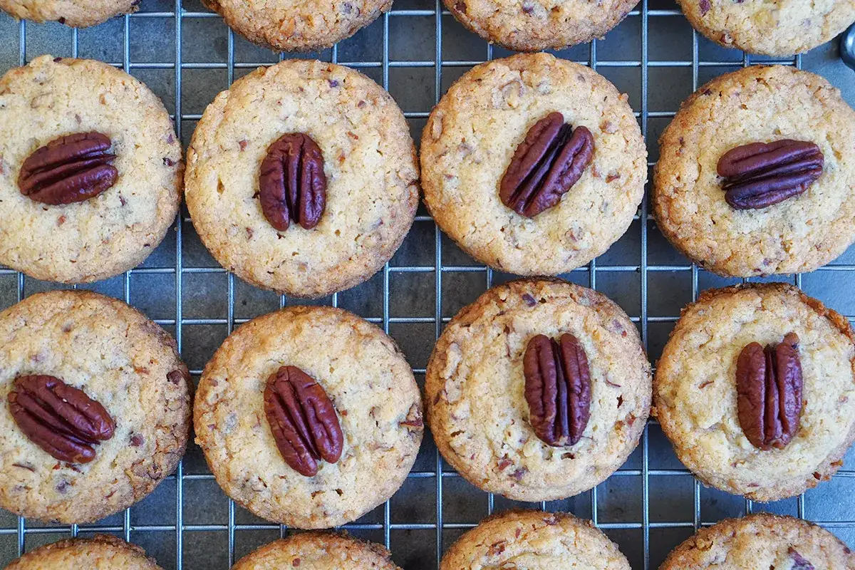 Reife pekannuss cookies, goldbraun gebacken, mit ganzen Pekann&uuml;ssen verziert, liegen auf einem Gitter.