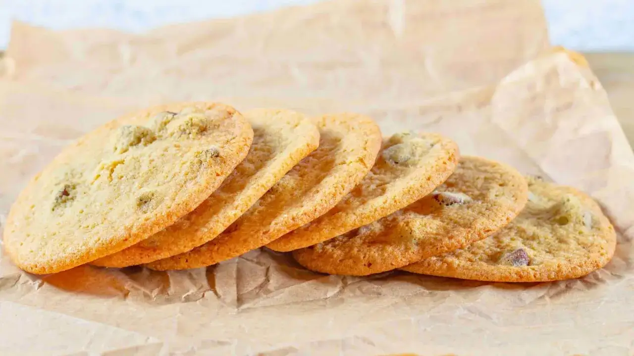 Fünf goldbraune Kekse, die nach einem einfachen Cookies Rezept gebacken wurden, liegen auf Backpapier.