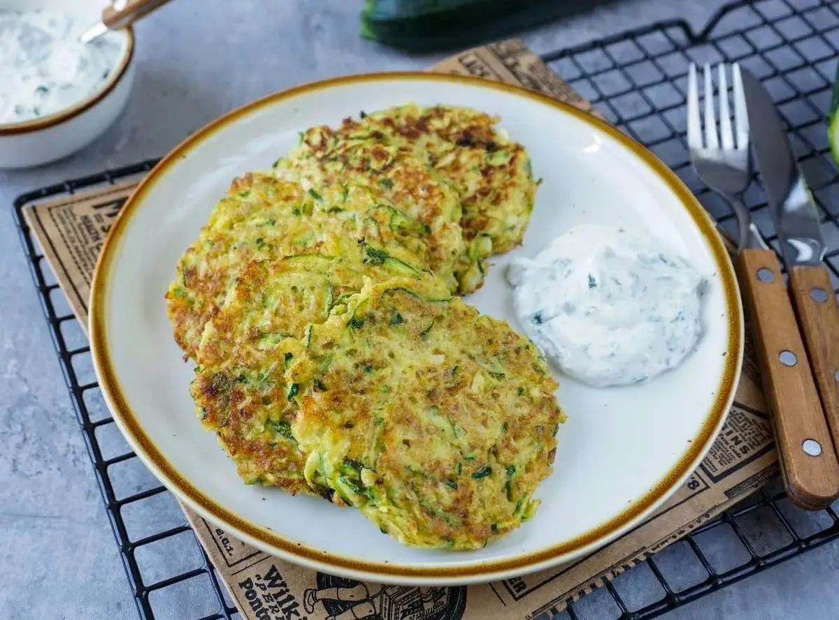 Zucchini-Puffer, goldbraun gebraten, serviert mit einem cremigen Dip. Ein leckerer Snack!