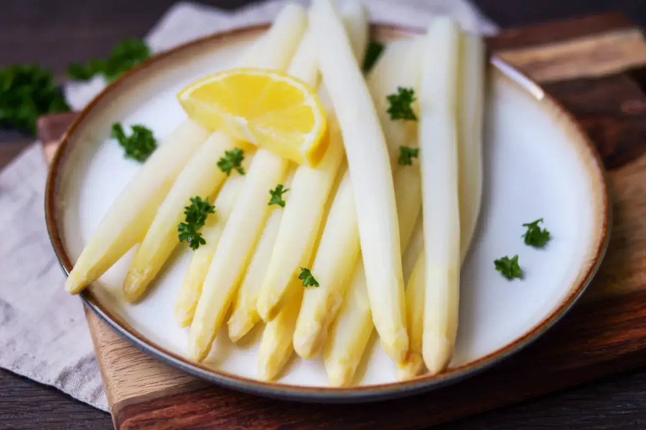 Frischer weißer Spargel, perfekt gekocht, garniert mit Petersilie und einer Zitronenspalte. Ein Genuss, der Lust auf mehr macht.