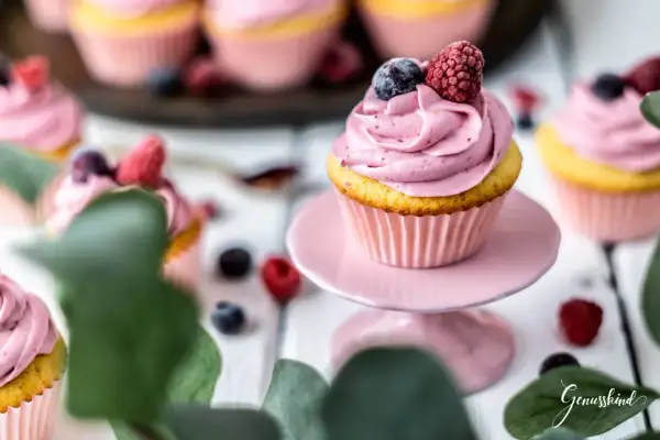 Ein köstliches Cupcake-Rezept mit rosa Frosting, garniert mit Blaubeeren und Himbeeren. Perfekt für süße Momente.