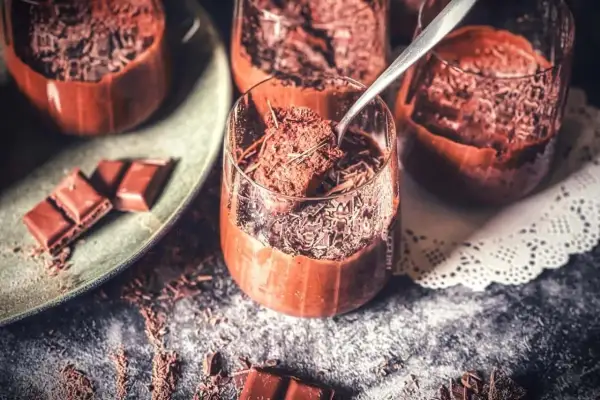 Schokoladenmousse in Gläsern, bestreut mit Schokostreuseln. Ein Löffel nimmt eine Portion auf. Perfekt für ein rezept mousse au chocolat ohne ei.
